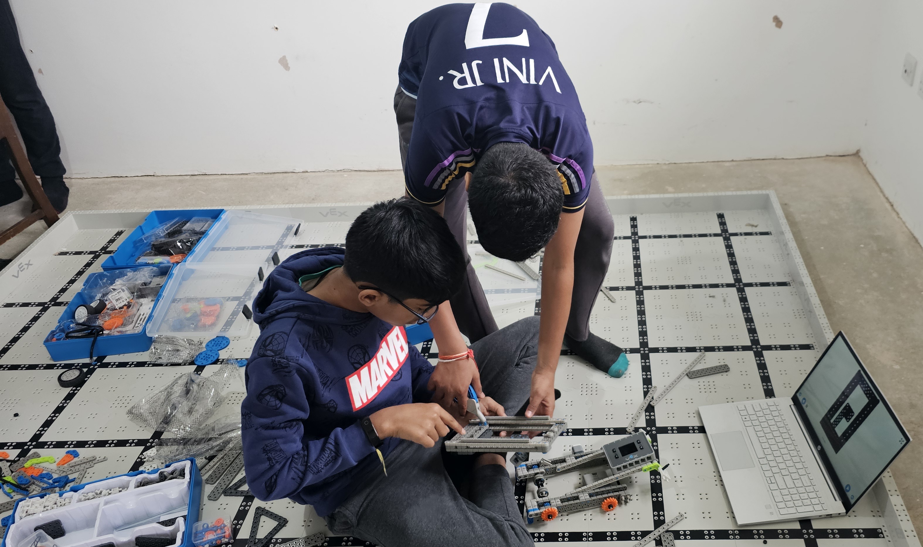 Students assembling a VEX robot on the build mat